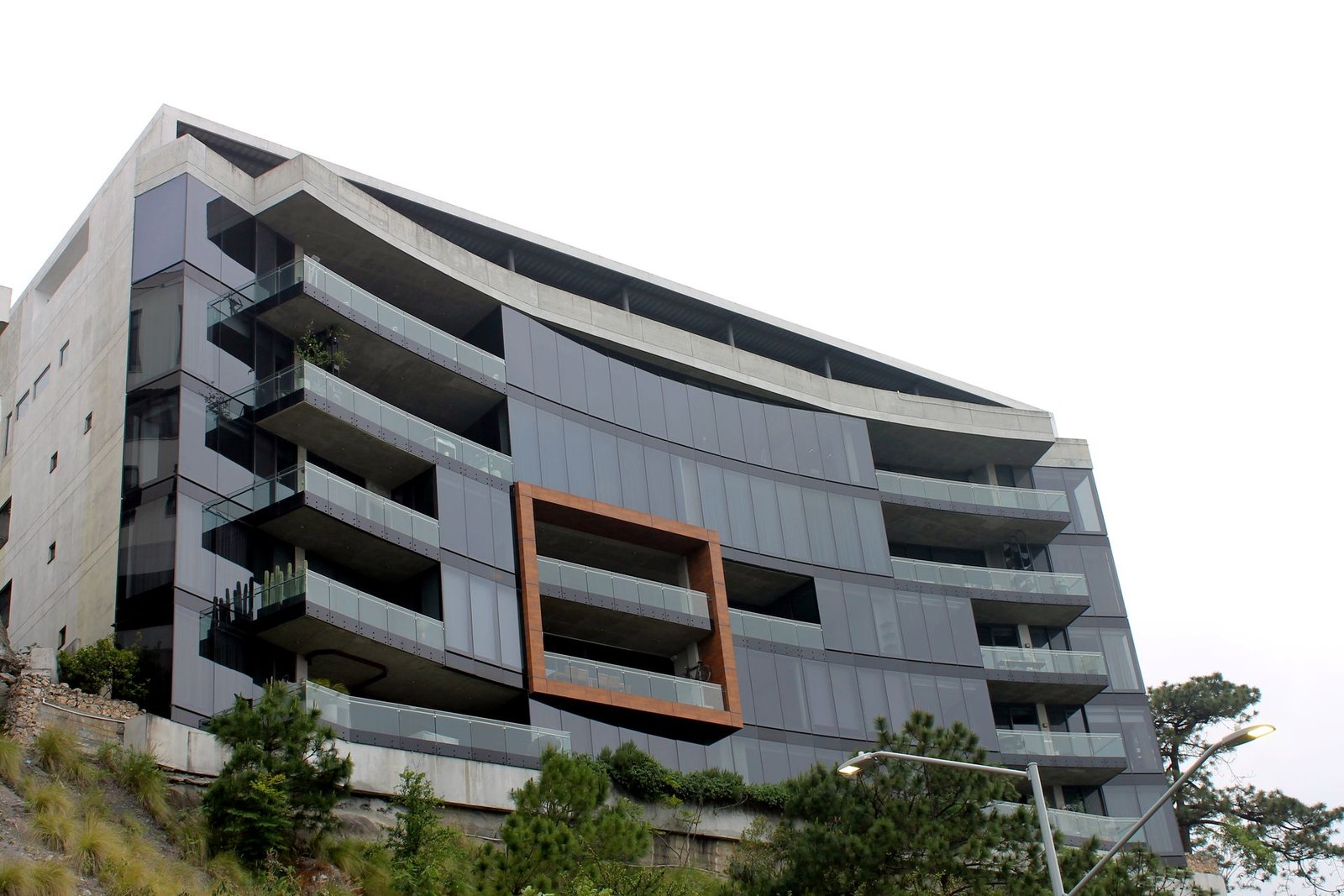 Edificio multifamiliar de fachada curva con barandales de cristal templado en cada balcón