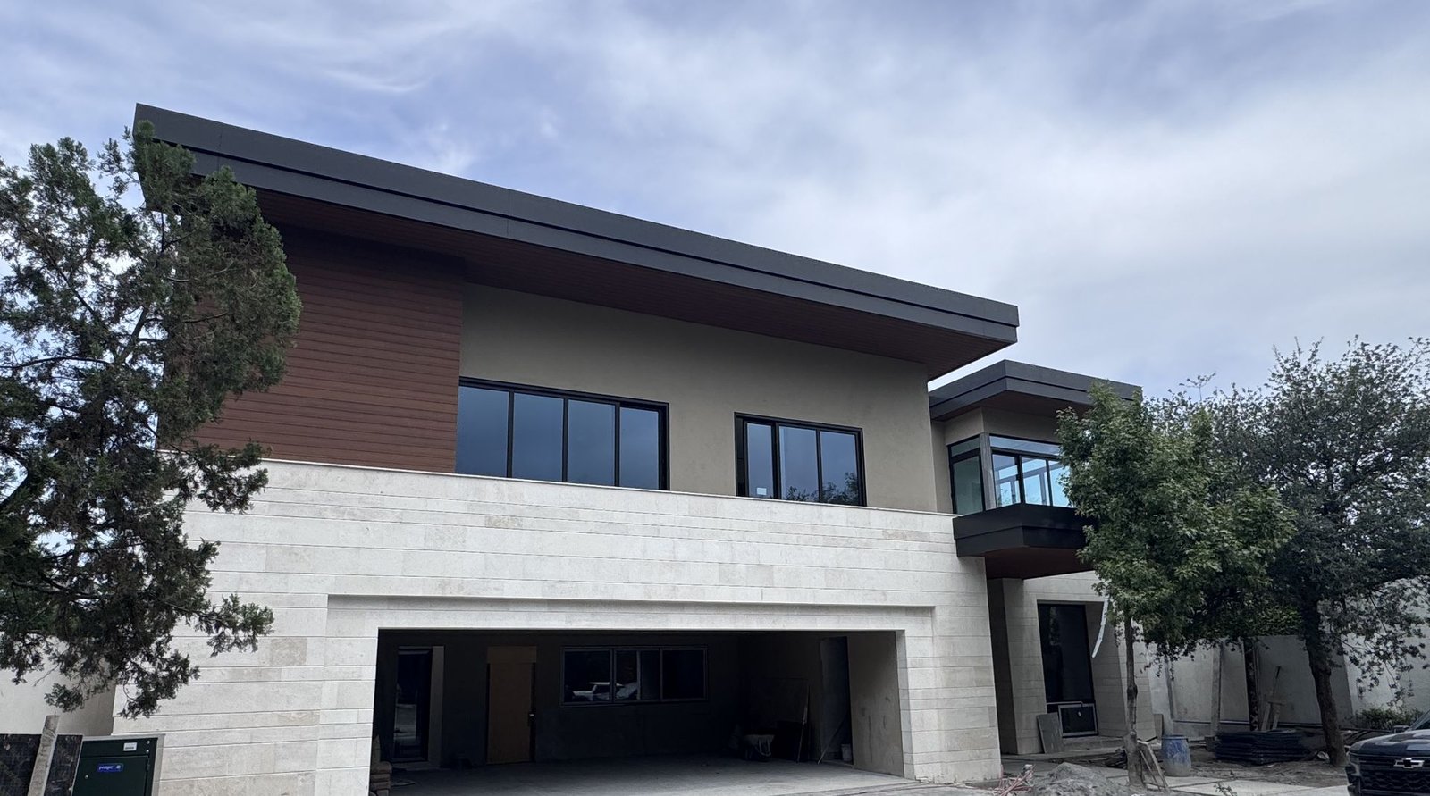 Fachada de residencia en San Pedro Garza García con recubrimiento de travertino y ventanería de PVC oscura